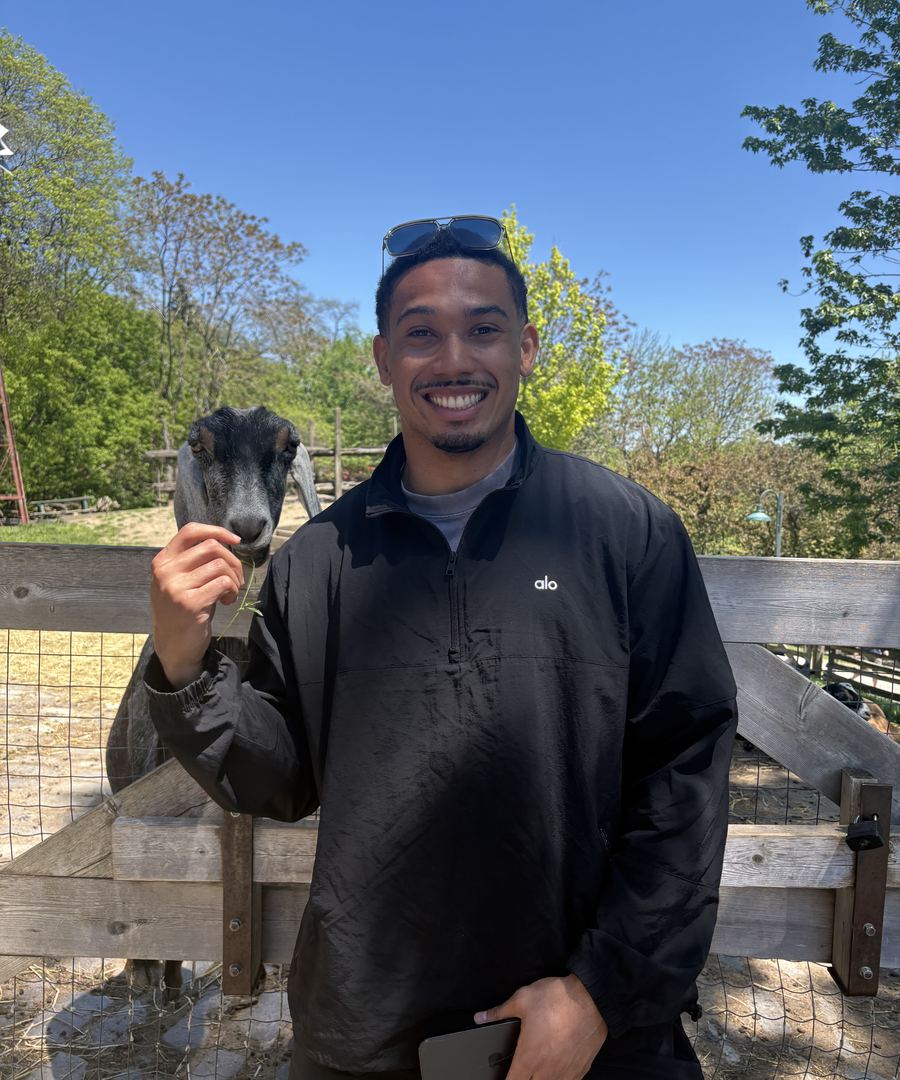 Devynn smiling while feeding a goat at a farm